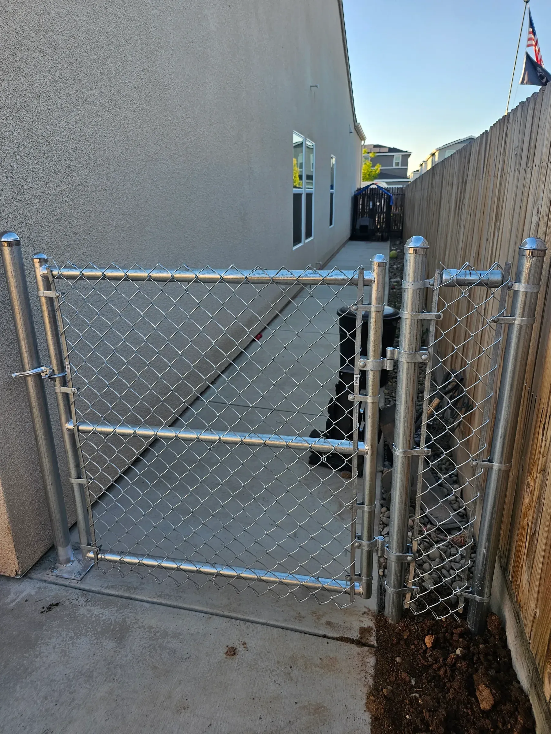 A galvanised chain link gate and fence closing off the side yard of a house.