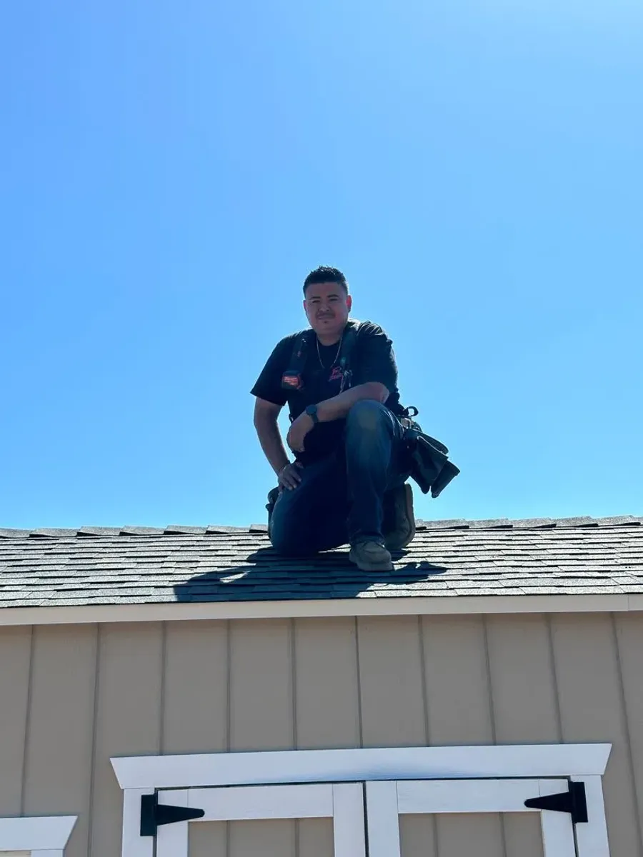 Fence contractor kneeling on a shed roof in Fresno, California