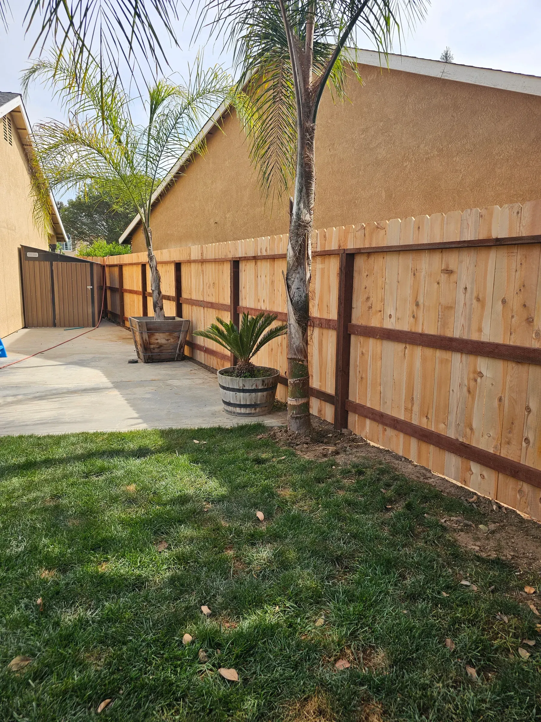 A framed wood fence around a back lawn, its horizontal rails visible across the face.