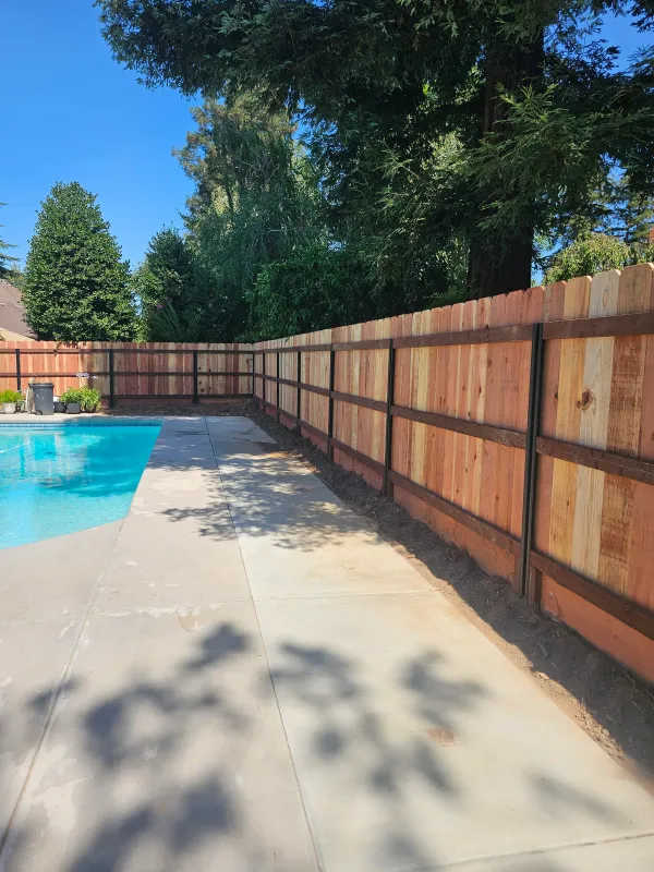 A framed wood fence running alongside a swimming pool on a Fresno-area property.