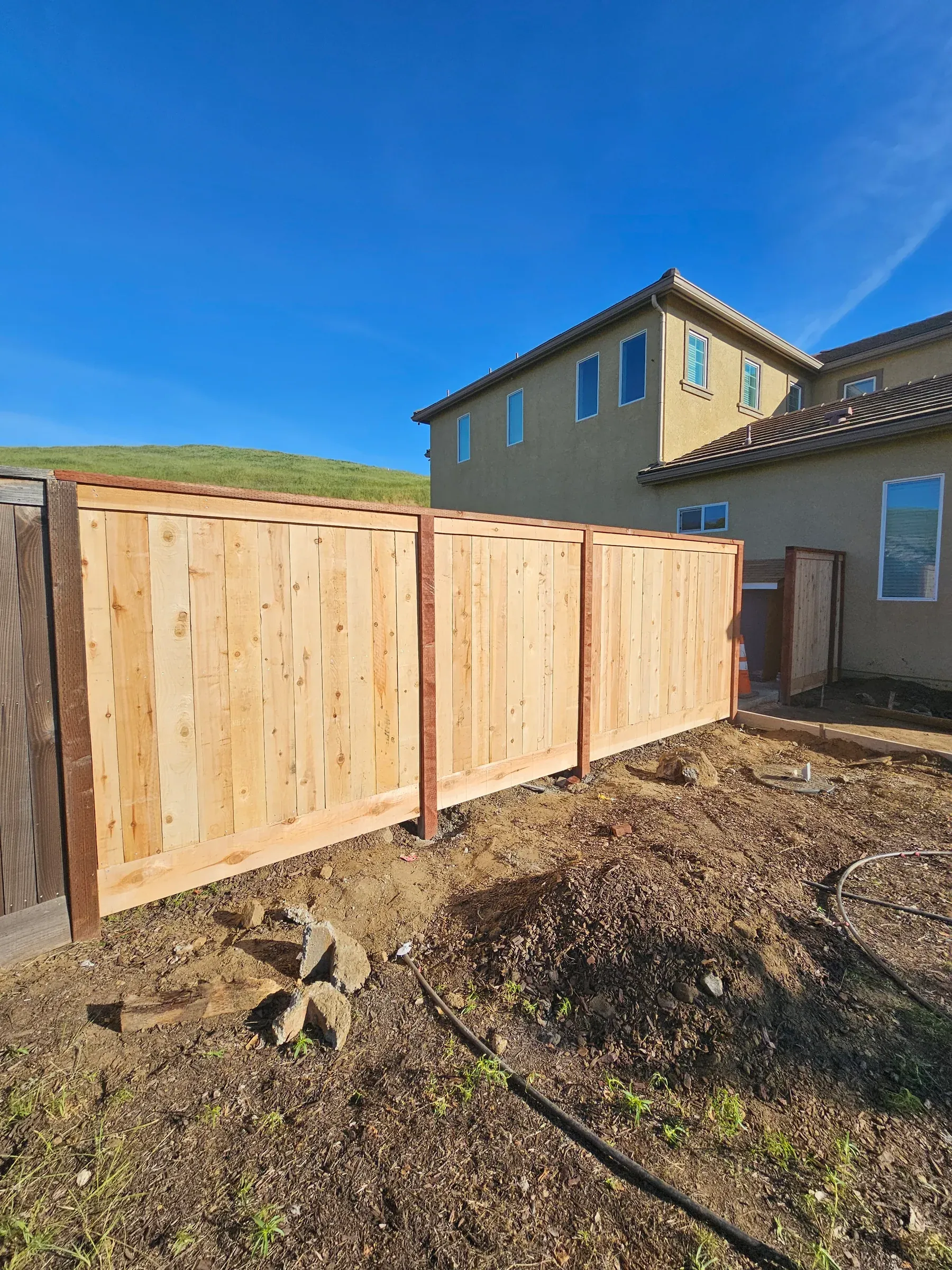 A new cedar fence standing finished beside a two-storey Fresno home on install day.