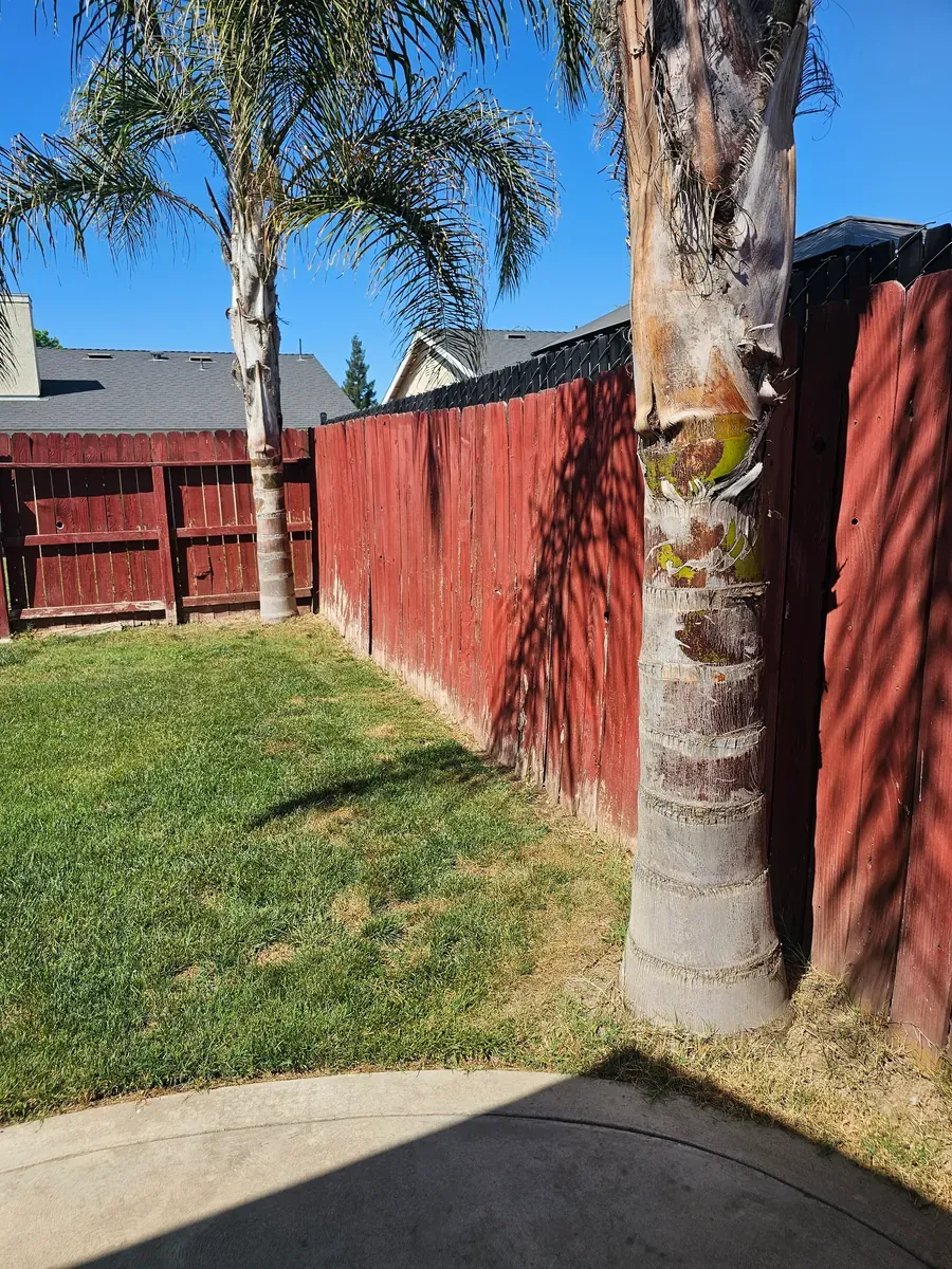 Red-stained wood fence behind a lawn in Fresno, California